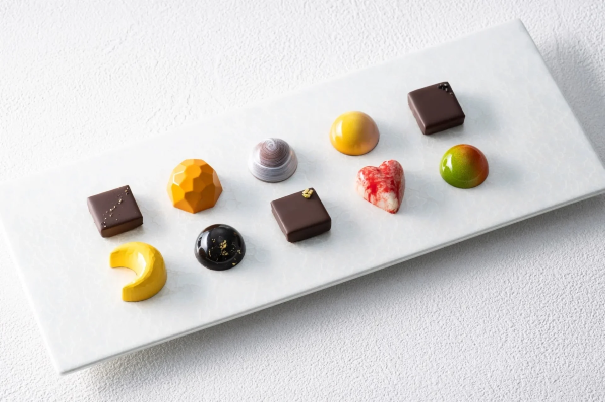 白い長方形の皿に、色とりどりや様々な形の美しいボンボンショコラが10個並べられています