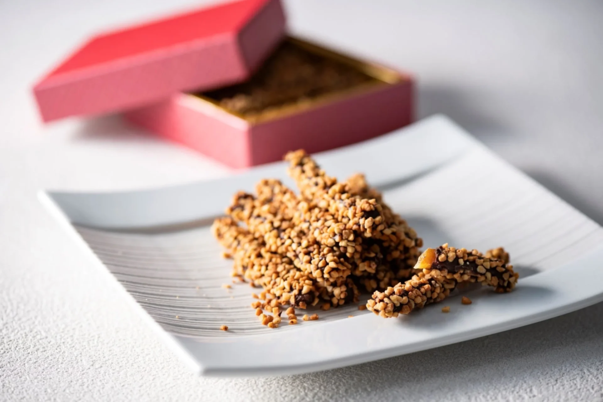 チョコレートと砕いたナッツでコーティングされたスティック状のお菓子が白い皿にきれいに盛り付けられています