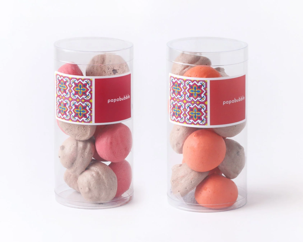 透明な円筒形の容器に、赤やオレンジ、茶色の丸いメレンゲ菓子が詰められています